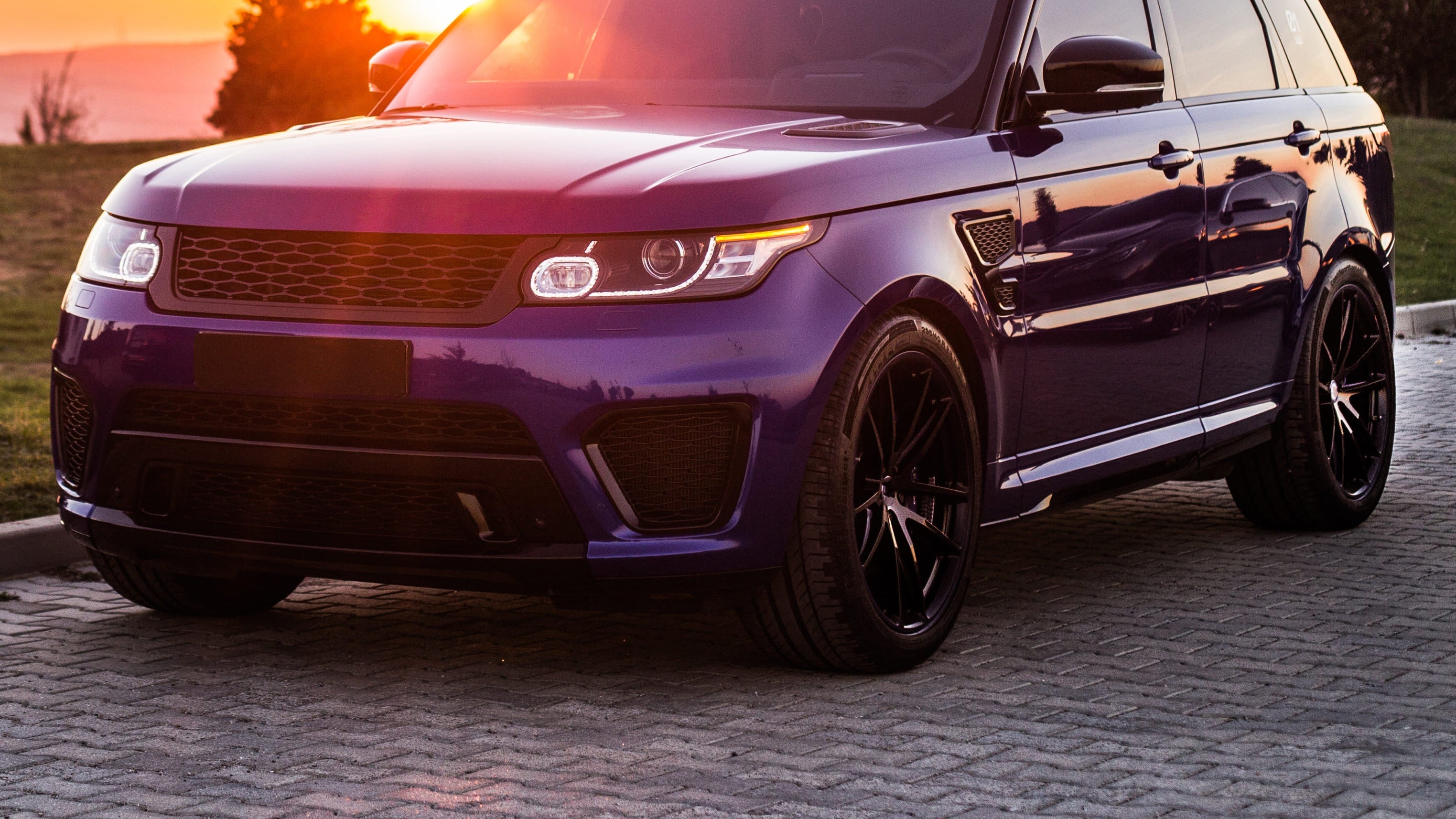 Luxury SUV parked on a scenic road with a sunset in the background